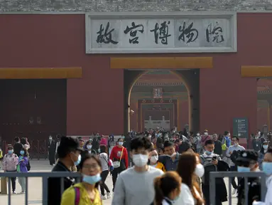 Pengunjung yang mengenakan masker untuk membantu mencegah penyebaran virus corona keluar dari Kota Terlarang selama liburan selama seminggu untuk Hari Nasional 1 Oktober, di Beijing, Rabu, (7/10/2020). (AP Photo/Andy Wong)