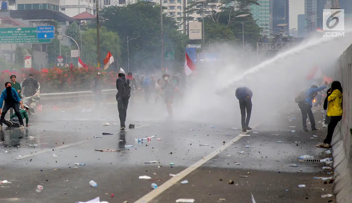 Mahasiswa mendapat semprotan air dari kendaraan water cannon polisi dalam demonstrasi menolak pengesahan RUU KUHP dan revisi UU KPK di depan Gedung DPR, Jakarta, Selasa (24/9/2019). Semprotan water cannon dan tembakan gas air mata memaksa mahasiswa mundur. (Liputan6.com/Faizal Fanani)