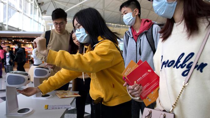 Para pelancong mengenakan masker wajah saat berada di Bandara Internasional Hong Kong di Hong Kong, Selasa (21/1/2020). Masker terjual habis dan pemeriksaan suhu di bandara dan stasiun kereta api menjadi norma baru di China menyusul merebaknya wabah virus corona.  (AP/Ng Han Guan)