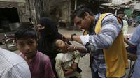 Seorang petugas kesehatan memberikan tetes vaksin polio kepada anak-anak saat kampanye vaksinasi polio dari rumah ke rumah di lingkungan Lahore, Pakistan, Senin (23/5/2022). Pakistan meluncurkan upaya anti-polio baru pada hari Senin, lebih dari seminggu setelah pejabat mendeteksi kasus ketiga tahun ini di wilayah barat laut negara itu yang berbatasan dengan Afghanistan. (AP Photo/K.M. Chaudary)