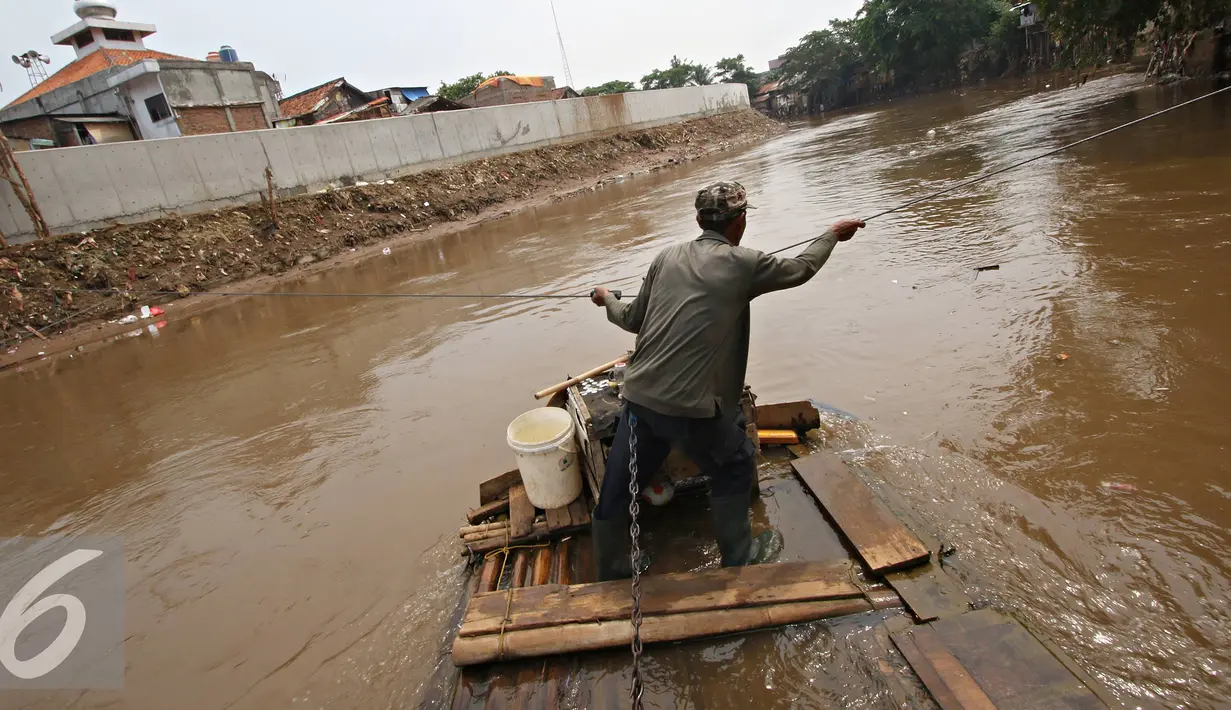 Pekerja saat menyebrangi perahu eretan di Kali Ciliwung, Jakarta, Senin (30/11). Tidak adanya fasilitas jembatan menyebabkan warga memilih eretan sebagai sarana penyeberangan sehari-hari, meskipun dengan kondisi seadanya. (Liputan6.com/Immnuel Antonius)