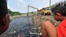 Anak-anak menyaksikan pengerukan sampah Kali Pisang Batu, Tarumajaya, Bekasi, Jawa Barat, Rabu (9/1). Petugas DLH Kabupaten Bekasi mulai membersihkan sampah setelah fenomena tersebut ramai diberitakan di media sosial. (Merdeka.com/Iqbal S. Nugroho)