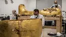 Para arkeolog merestorasi sarkofagus atau peti mati emas Firaun Tutankhamun di laboratorium restorasi Grand Egyptian Museum (GEM), Giza, Mesir, Senin (13/4/2020). Firaun Tutankhamun merupakan Raja Mesir Kuno yang memerintah antara tahun 1342-1325 SM. (Khaled DESOUKI AFP)