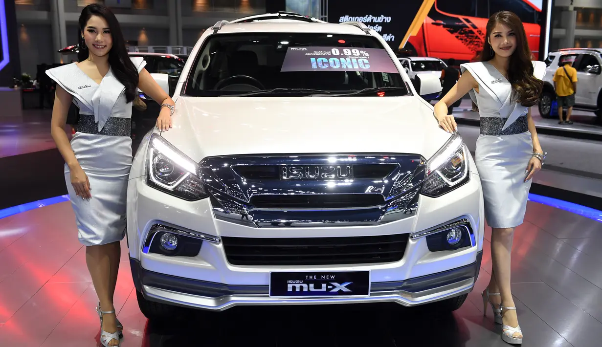 Dua model berpose di samping ISUZU MU-X 2019 selama Thailand International Motor Expo di Bangkok (29/11). (AFP Photo/Lillian Suwanrumpha)