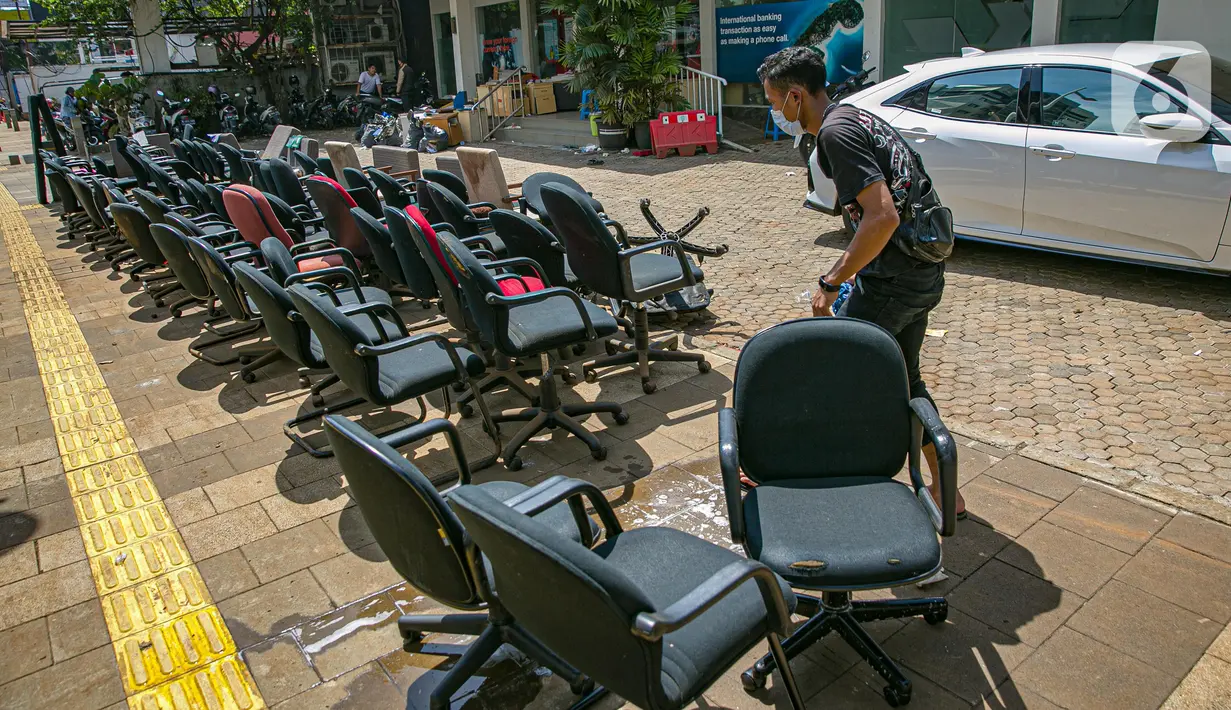 Karyawan membersihkan peralatan kantor pascabanjir di salah satu bank swasta di Kemang, Jakarta, Selasa (23/2/2021). Karyawan pertokoan, perkantoran, hingga perbankan mulai membersihkan sisa lumpur dari banjir yang melanda kawasan tersebut pada 20 Februari 2021 lalu. (Liputan6.com/Faizal Fanani)