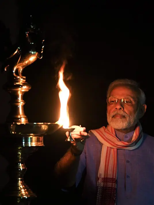 Perdana Menteri India Narendra Modi menyalakan lampu minyak untuk menandai perjuangan melawan pandemi virus corona COVID-19 di New Delhi, India, Minggu (5/4/2020). Modi mengatakan aksi ini akan menghilangkan kegelapan yang diciptakan oleh COVID-19. (Twitter via AP)