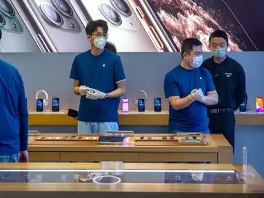 Para pekerja mengenakan masker saat menjaga Apple Store yang dibuka kembali di Beijing, China, Jumat (14/2/2020). Apple kembali membuka tokonya di China setelah pada awal Februari lalu menutup seluruhnya karena khawatir terhadap wabah virus corona. (AP Photo/Mark Schiefelbein)