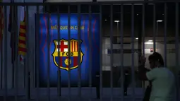 Seorang penggemar mengintip melalui pagar pintu masuk kantor Barcelona di stadion Camp Nou di Barcelona, Spanyol, Kamis (5/8/2021). Messi sudah berstatus tanpa klub sejak tanggal 1 Juli 2021 mengingat kontraknya bersama Barcelona usai. (AP Photo/Joan Monfort)