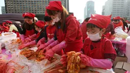 Seorang anak ikut membuat kimchi, hidangan tradisional Korea Selatan, selama Festival Kimchi tahunan di pusat kota Seoul, Jumat (3/11). Acara tersebut dibuat oleh para sukarelawan yang hasilnya didonasikan untuk kaum minoritas. (AP Photo/Ahn Young-joon)
