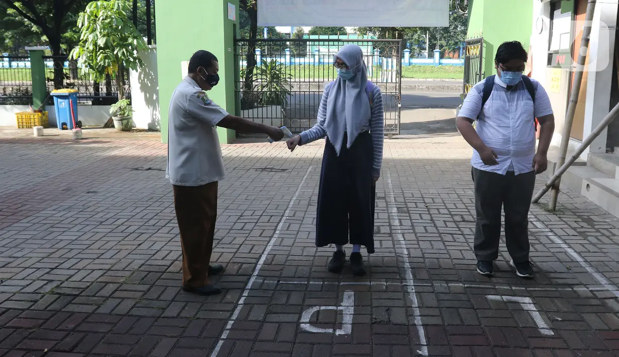 Petugas mengec suhu siswa sabun sebelum mengikuti kegiatan belajar tatap muka di SMP Negeri 2 Bekasi, Selasa (23/3/2021). Kegiatan belajar mengajar secara tatap muka di SMPN 2 Kota Bekasi akan dilakukan secara bergiliran. (Liputan6.com/Herman Zakharia)
