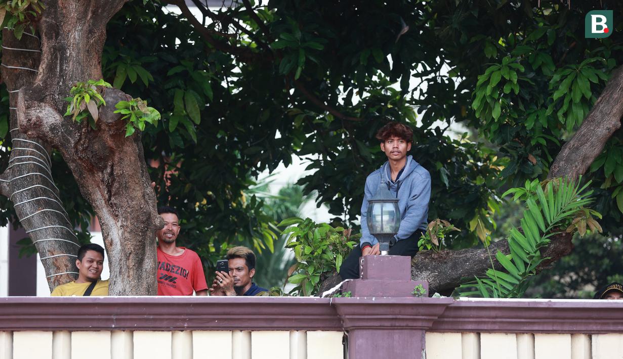 Penonton menyaksikan pertandingan antara Arema FC melawan PSM Makassar pada laga BRI Liga 1 di Stadion PTIK, Jakarta, Sabtu (4/2/2023). Ada yang dari atap Mess, atas pohon, hingga mobil pemadam kebakaran. (Bola.com/M Iqbal Ichsan)