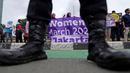Seorang petugas polisi berjaga-jaga saat para aktivis membentangkan spanduk dalam unjuk rasa Hari Perempuan Internasional di Jakarta, Indonesia, Jumat, 8 Maret 2024. (AP Photo/Dita Alangkara)