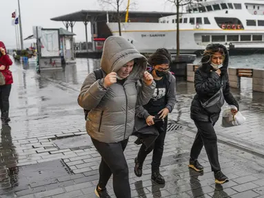 Orang-orang berlarian di bawah hujan deras selama hari badai di Istanbul, Turki, Senin (29/11/2021). Sedikitnya empat orang tewas pada Senin saat badai dahsyat disertai angin kencang menghantam kota metropolitan Istanbul di Turki, kata kantor gubernur Istanbul. (AP Photo)