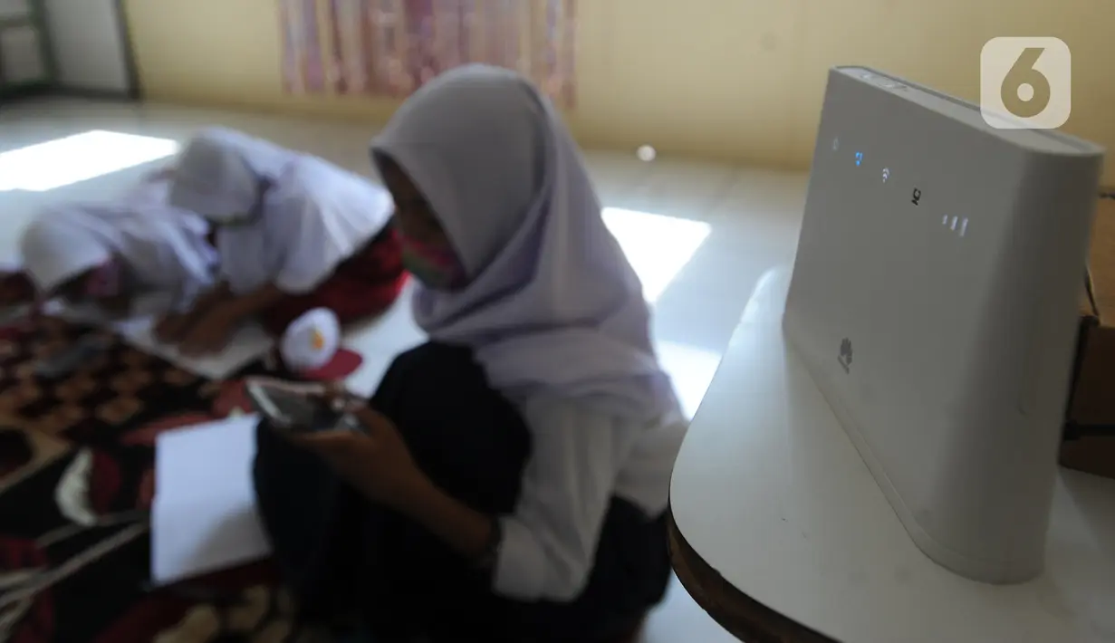 Murid-murid SD dan SMP belajar dengan memanfaatkan wifi gratis di Balai RW kawasan Tegal Gundil, Bogor, Jawa Barat, Senin (21/9/2020). Pemkot Bogor menyebar lebih dari 50 titik wifi publik gratis untuk menunjang Pembelajaran Jarak Jauh (PJJ) siswa di Kota Bogor. (merdeka.com/Arie Basuki)