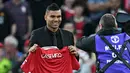 Gelandang Manchester United Casemiro berpose dengan jersenya saat diperkenalkan kepada para pendukung sesaat sebelum laga MU vs Liverpool dimulai di stadion Old Trafford, Senin (22/8/2022). Casemiro secara resmi akan mengakhiri masa sembilan tahun yang sangat sukses di Real Madrid dengan 18 trofi, termasuk lima Liga Champions. (Paul ELLIS / AFP)