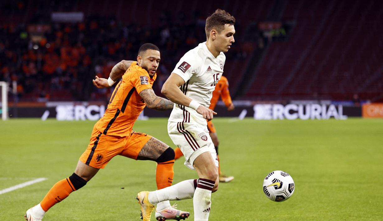 Gelandang Latvia, Vladislavs Fyodorovs (kanan) menguasai bola dibayangi striker Belanda, Memphis Depay dalam laga Kualifikasi Piala Dunia 2022 Zona Eropa Grup G di Johan Cruijff Arena, Amsterdam, Sabtu (27/3/2021). Belanda menang 2-0 atas Latvia. (AFP/Maurice van Steen/ANP)
