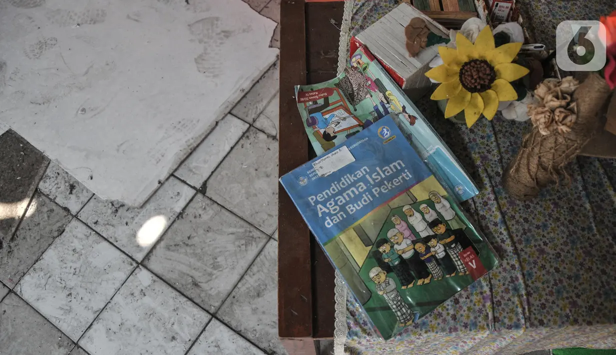 Kondisi meja guru lengkap dengan buku pelajaran yang hingga kini belum dibersihkan di SDN Pancoranmas 3, Depok, Jawa Barat, Minggu (24/7/2022). Dua ruang kelas di SDN Pancoranmas 3 yang rusak akibat terjangan angin kencang dan hujan deras pada pertengahan April 2022 lalu itu hingga kini tak kunjung diperbaiki sehingga murid terpaksa mengungsi belajar di kelas lain.  (merdeka.com/Iqbal S. Nugroho)