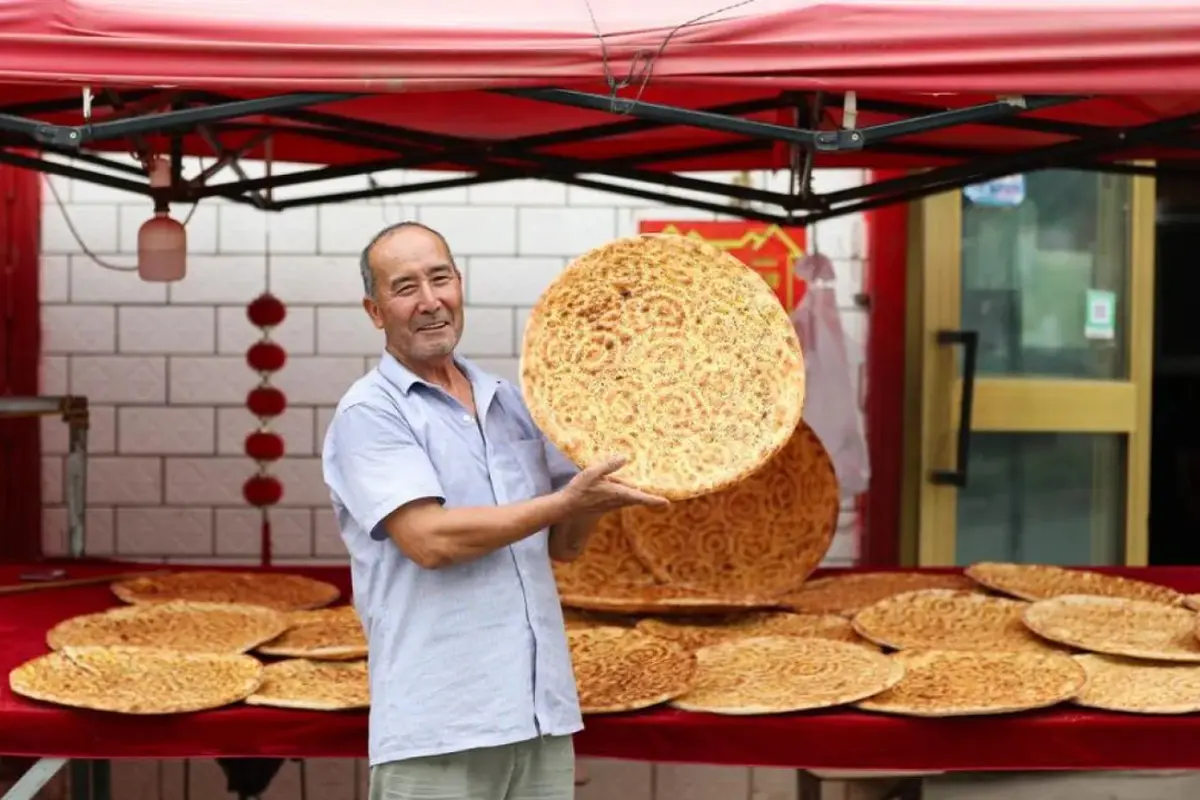Rishit Himit menunjukkan roti naan buatannya di Kota Kuqa, Daerah Otonom Uighur Xinjiang, China, pada 21 Juli 2025 (Dok. ANTARA/Xinhua/Wang Jingqiang).