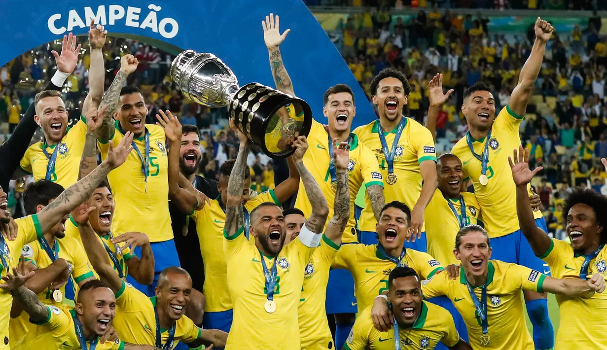 Pemain belakang timnas Brasil, Dani Alves mengangkat trofi Copa America 2019 saat berselebrasi bersama rekan setimnya setelah mengalahkan Peru pada partai final di Maracana Stadium, Rio de Janeiro, Senin (8/7/2019) dini hari WIB. Brasil menundukkan Peru dengan skor 3-1. (AP/Victor R. Caivano)