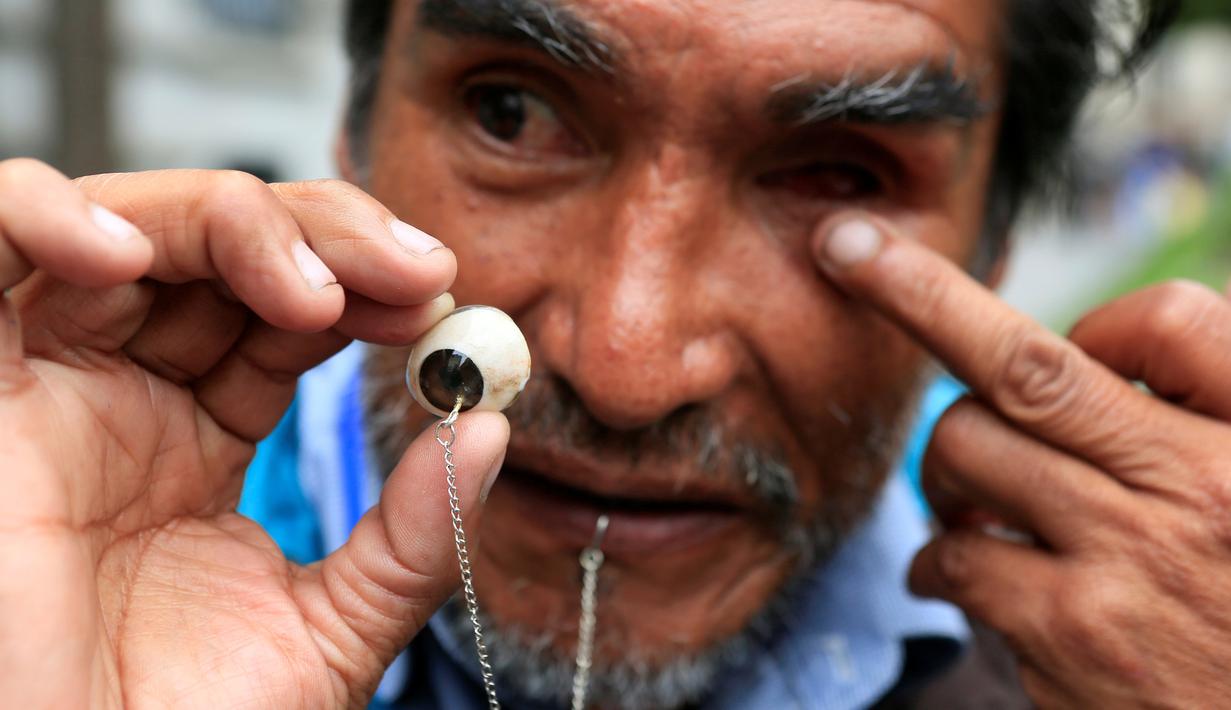 Edwin Morales menunjukan mata palsunya yang dirantai saat aksi menuntut subsidi penyandang cacat di La Paz, Bolivia (12/4). Edwin menuntut Presiden Evo Morales untuk meningkatkan subsidi USD 70 setara dengan Rp 900 ribu per bulan. (REUTERS/David Mercado)