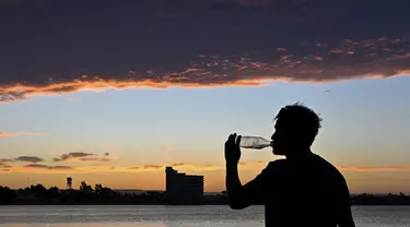 Seorang pria meminum air di bawah sinar matahari di sebuah pantai di Puerto Madryn, provinsi Chubut, Argentina pada tanggal 26 Januari 2024. (MAXI JONAS/AFP)