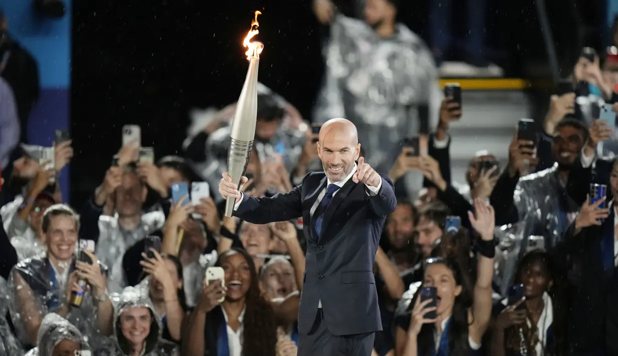 Acara dimulai dengan legenda sepak bola Prancis, Zinedine Zidane, yang menyerahkan obor kepada petenis raja tanah liat, Rafael Nadal. (AP Photo/Natacha Pisarenko)