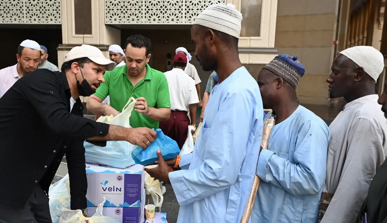 <p>Penduduk Makkah membagikan makanan, buah-buahan, dan air mineral ke setiap orang yang lewat. (Sajjad HUSSAIN/AFP)</p>