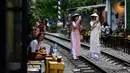 Foto pada 8 Juni 2019 menunjukkan uris mengenakan kostum tradisional Vietnam berswafoto di tengah jalur kereta api populer di Hanoi. Di ibu kota Vietnam tersebut rel-rel kereta yang berada di permukiman padat penduduk dijadikan destinasi wisata selfie. (Photo by Manan VATSYAYANA / AFP)