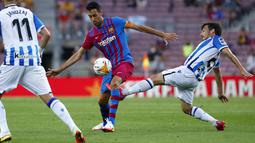 Gelandang Real Sociedad, David Silva berusaha merebut bola dari gelandang Barcelona, Sergio Busquets pada pertandingan La Liga Spanyol di stadion Camp Nou di Barcelona, Spanyol, Senin (16/8/2021). Barcelona menang atas Sociedad 4-2.  (AP Photo/Joan Monfort)