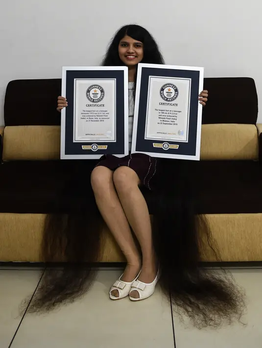 Gadis asal India, Nilanshi Patel (17) berpose dengan sertifikat Guinness World Records 2018 (kiri) dan 2019 sebagai rambut terpanjang dari kategori remaja di kota Modasa, sekitar 110 Km dari Ahmedabad, Minggu (19/1/2020). (SAM PANTHAKY/AFP)