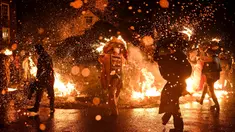 Para pria meletakkan tong-tong mereka yang menyala di atas api di akhir prosesi mereka melalui jalan-jalan selama festival tahunan Allendale Tar Barrel di Allendale, Inggris utara, pada malam hari antara tanggal 31 Desember 2024 dan 1 Januari 2025. (Oli SCARFF/AFP)
