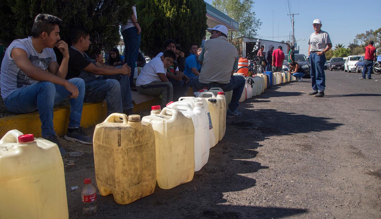 Warga antre menggunakan jerigen di tengah kelangkaan BBM di sebuah SPBU di Morelia, Meksiko, Selasa (8/1). Kelangkaan BBM akibat terjadinya pencurian dari jaringan pipa dan dari internal Pemex, perusahaan minyak milik negara. (ENRIQUE CASTRO/AFP)