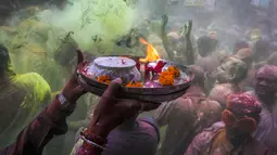 Umat Hindu dengan persembahan berjalan menuju mobil yang membawa patung dewa Krishna selama festival Holi di Kolkata, India, Minggu, 5 Maret 2023. Dalam festival Holi di India, warga saling melempar serbuk warna-warni.(AP Photo/Bikas Das)