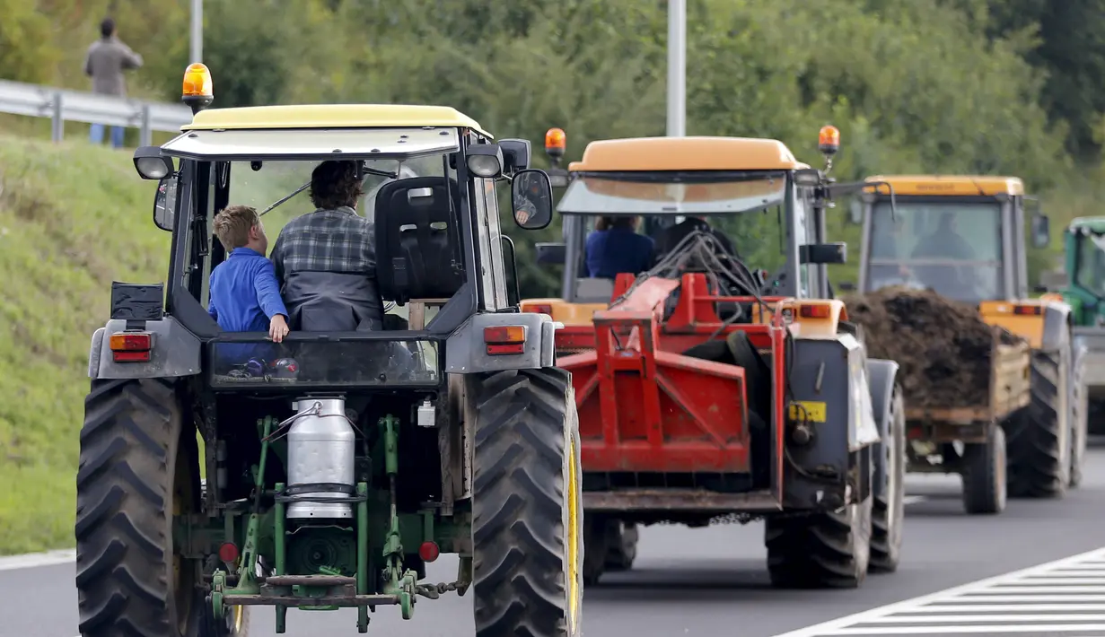 Traktor milik peternak sapi perah berjalan menuju jalan tol atau jalan bebas hambatan untuk melakukan aksi protes di Battice, Belgia, Kamis (30/7/2015). Aksi protes tersebut berkaitan dengan rendahnya harga jual susu. (REUTERS/Francois Lenoir)