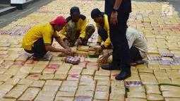 Petugas merapihkan barang bukti narkoba jenis ganja saat rilis di Polda Metro, Jakarta, Senin (30/7). Sebanyak 1.434 kg ganja jaringan Aceh-Jakarta-Bogor diamankan petugas berikut 6 orang tersangka. (Merdeka.com/Arie Basuki)