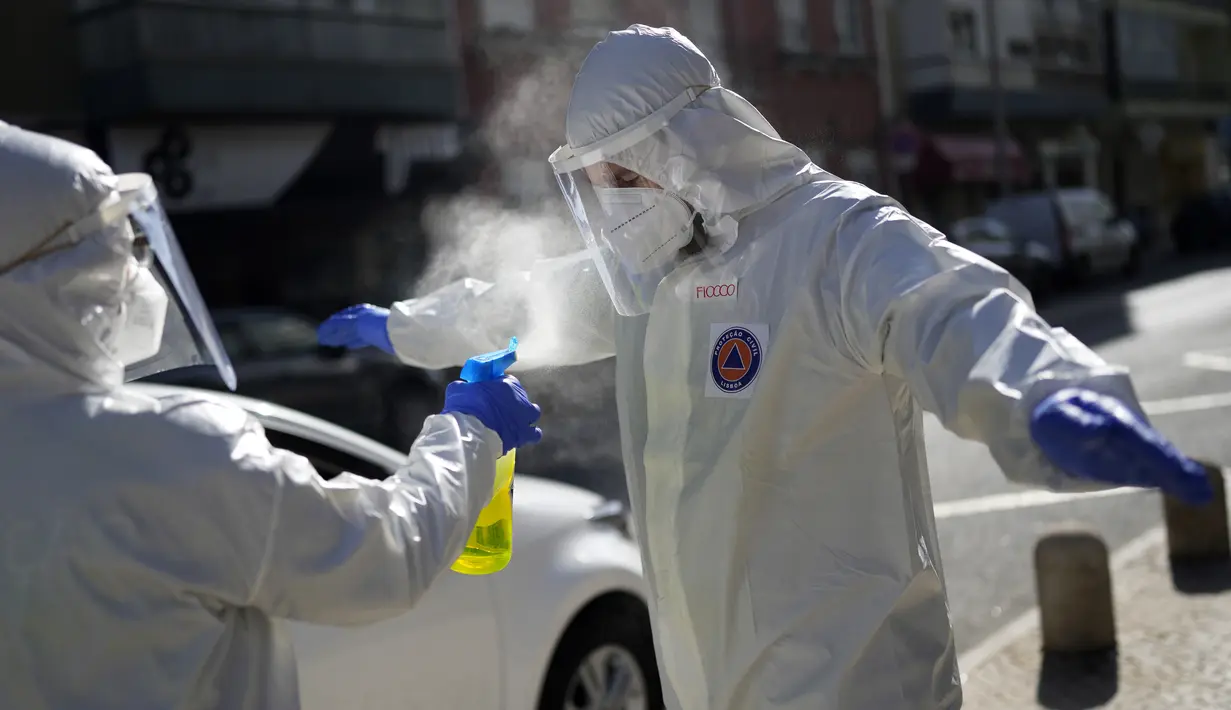Pekerja Lisbon Civil Protection menyemprot rekannya dengan disinfektan setelah mengunjungi rumah pemilih dalam isolasi COVID-19, 25 Januari 2022. Pekerja kota se-Portugal mengunjungi panti jompo dan orang dalam isolasi guna mengumpulkan suara untuk Pemilu 30 Januari mendatang. (AP/Armando Franca)