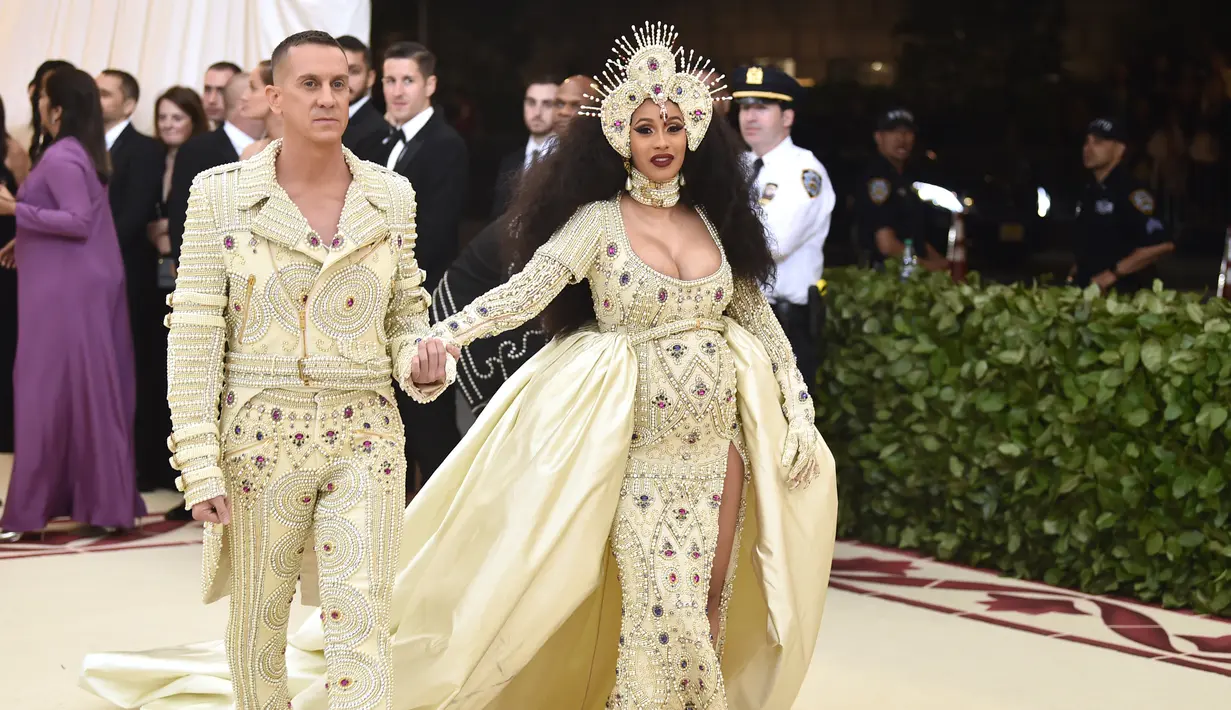 Penyanyi Cardi B didampingi Jeremy Scott saat menghadiri Met Gala 2018 di Metropolitan Museum of Art, New York (7/5). Cardi B terlihat mengenakan gaun yang dihiasi manik-manik saat menghadiri Met Gala 2018. (Photo by Evan Agostini/Invision/AP)