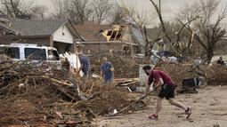 Jarrod Schneider, yang tinggal di Oxford Drive di Round Rock, Texas, membantu tetangganya membersihkan setelah tornado merusak beberapa rumah di jalan, Senin (21/3/2022). (Jay Janner/Austin American-Statesman via AP)