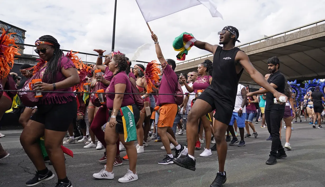 Sebuah pesta pora menari dengan para pemain selama Karnaval Notting Hill tahunan di London barat, Senin (29/8/2022). Karnaval yang kembali ke jalanan untuk pertama kalinya dalam dua tahun, setelah digagalkan oleh pandemi, adalah salah satu perayaan festival terbesar dari jenisnya di Eropa. (AP Photo/Alberto Pezzali)