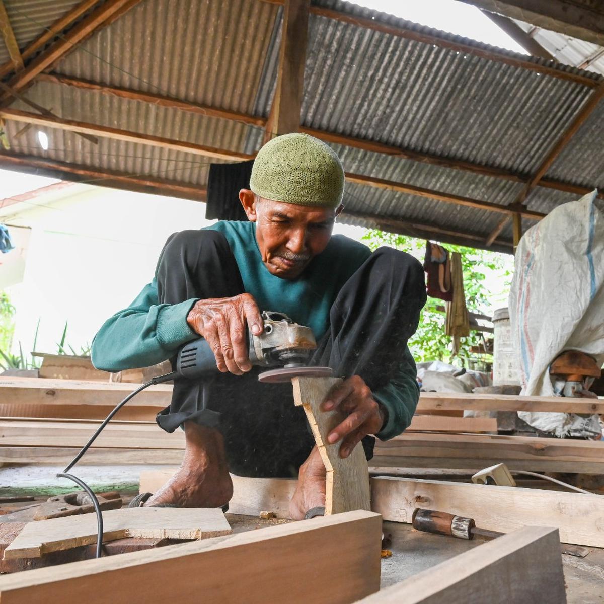 Utoh Amad sedang menghaluskan permukaan kayu untuk Canang Ceureukeh