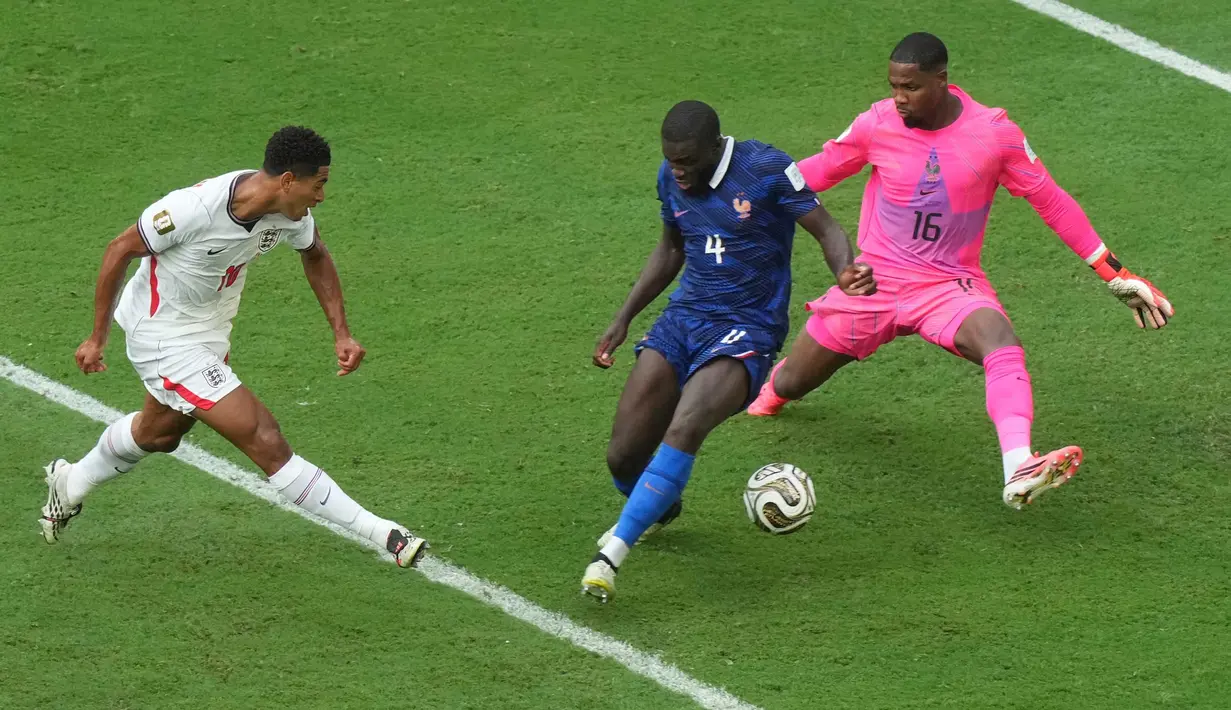 Pemian Inggris Jude Bellingham menendang bola melewati pemain Prancis Dayot Upamecano kiper Mike Maignan untuk mencetak gol keenam mereka selama pertandingan sepak bola perebutan tempat ketiga Piala Dunia antara Prancis dan Inggris di Miami Gardens, Florida, Sabtu, 18 Juli 2026. (AP Photo/Marta Lavandier)