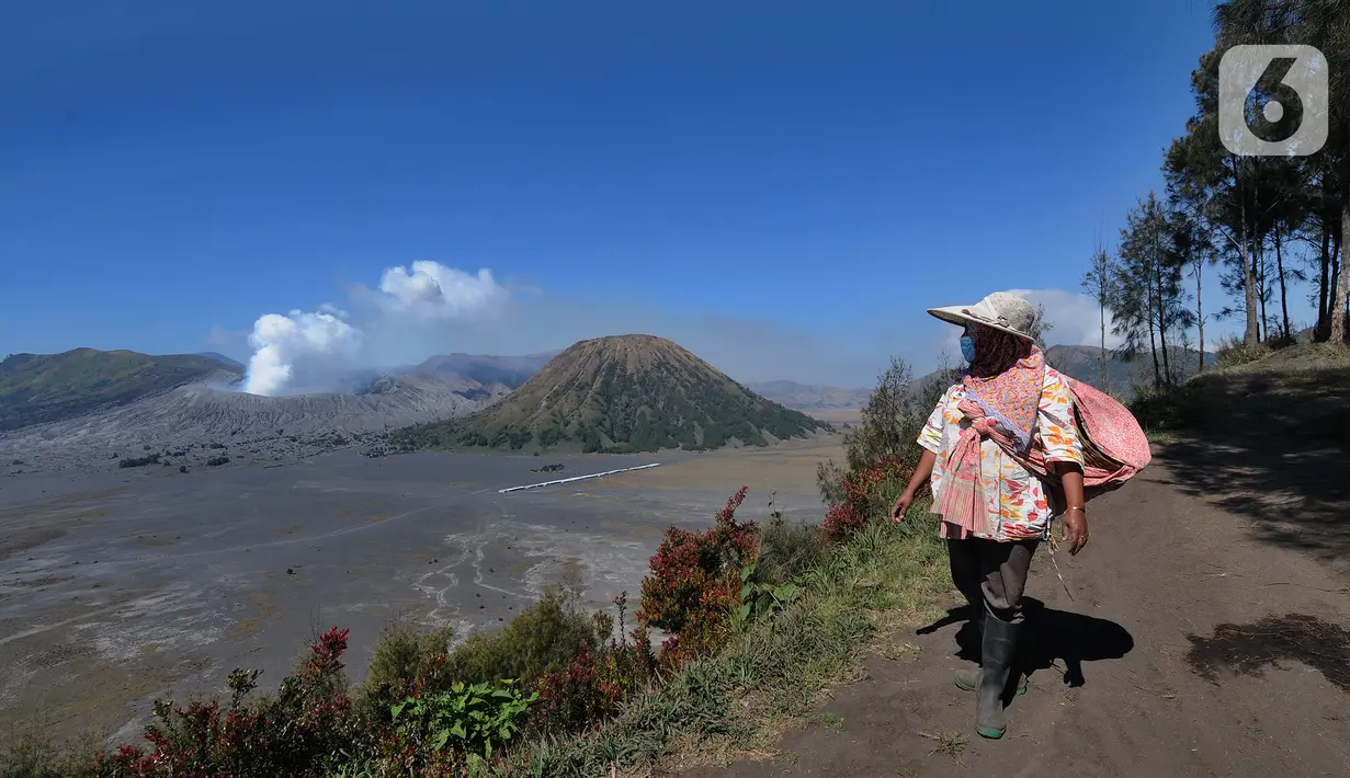 Warga melintas jalan dengan latar belakang kaldera Gunung Bromo di kawasan Cemoro Lawang, Probolinggo, Jawa Timur, Kamis (9/9/2021).  Kawasan kaldera Gunung Bromo dan hamparan pasir yang masih ditutup karena pemberlakuan PPKM Darurat. (merdeka.com/Arie Basuki)