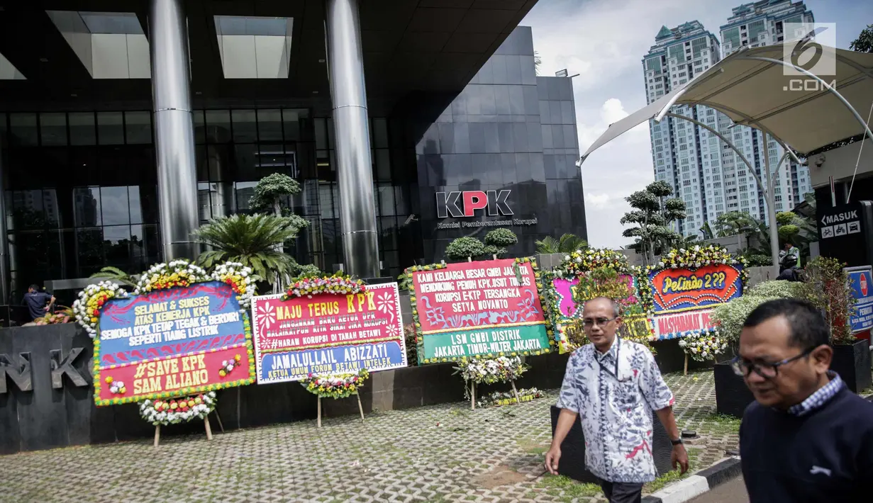 Warga melintas dekat karangan bunga berisi dukungan pada KPK di halaman Gedung KPK, Jakarta, Senin (20/11). Karangan bunga tersebut sebagai bentuk dukungan masyarakat kepada KPK terhadap pemberantasan kasus korupsi e-KTP. (Liputan6.com/Faizal Fanani)