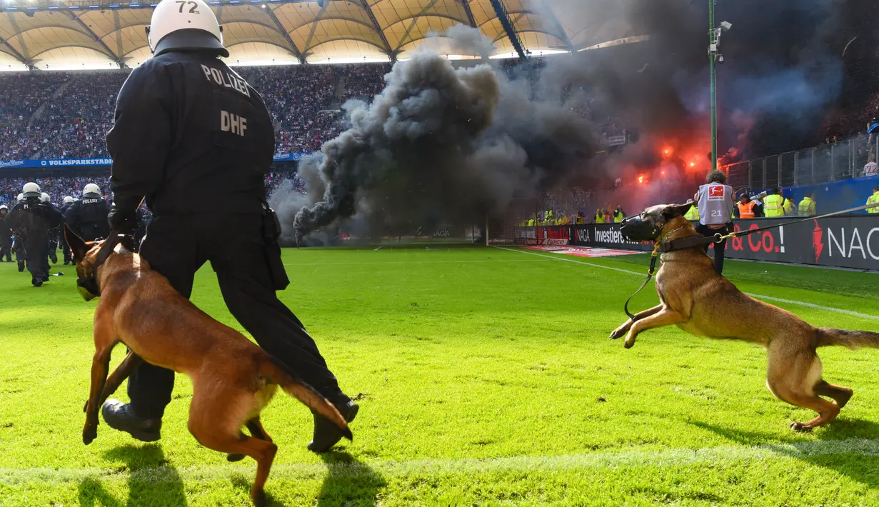 Petugas kepolisian berusaha menenangkan suporter yang mengamuk saat pertandingan antara Hamburg SV melawan VfL Borussia Moenchengladbach di Volksparkstadion, Sabtu (12/5/2018). Hamburg SV terdegradasi dari Bundesliga Jerman. (AP/Michael Sohn)