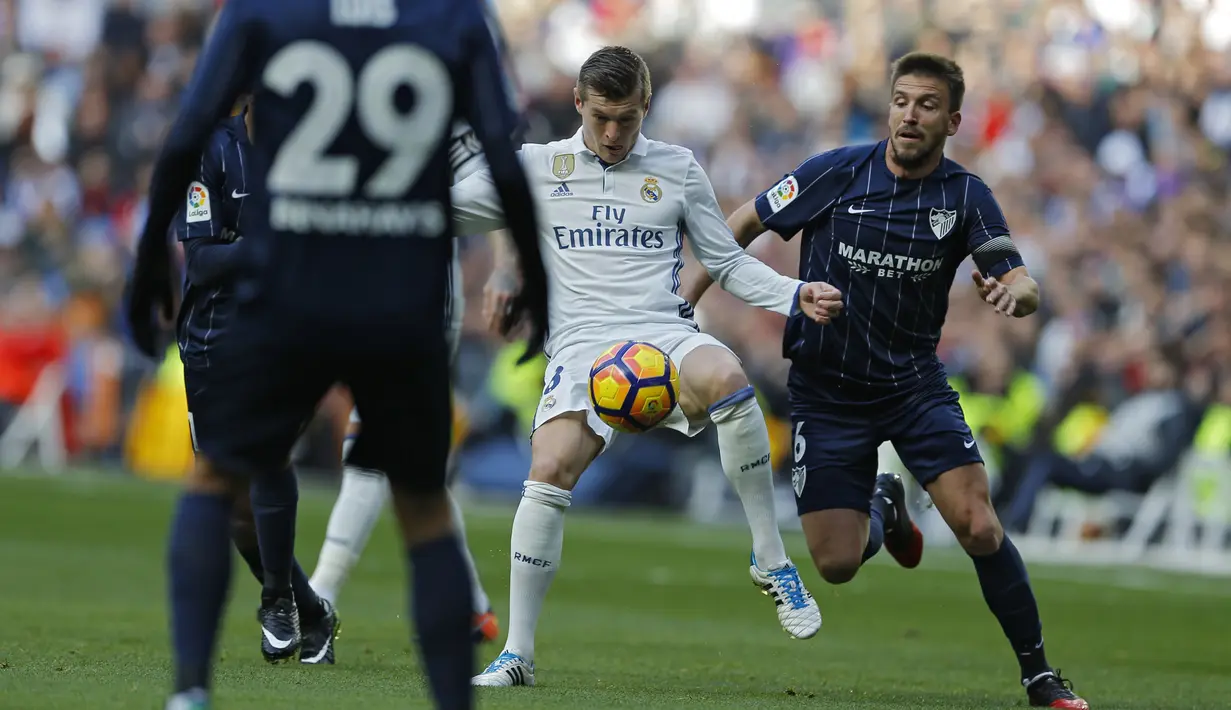 Toni Kroos (tengah) berusaha menerobos ketatnya pertahanan Malaga pada lanjutan La Liga di Santiago Bernabeu stadium, Madrid, Sabtu (21/1/2017). Madrid menang 2-1. (AP/Francisco Seco)