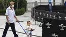 Seorang pria tua mendorong seorang anak di dekat barikade di luar taman hiburan Universal Studios selama uji coba di Beijing (31/8/2021). Universal Studios mengumumkan Senin, 30 Agustus 2021, bahwa taman hiburan pertamanya di China akan dibuka bulan September. (AP Photo/Ng Han Guan)