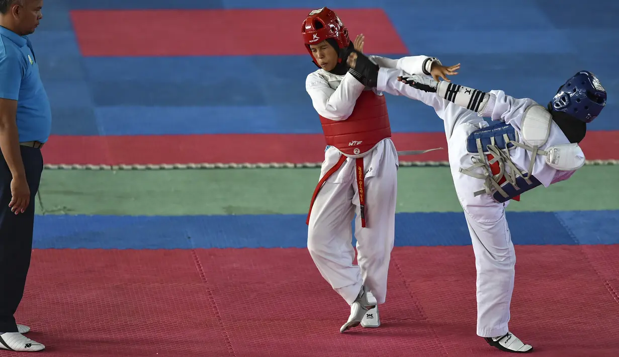 Dua peserta perempuan saat bertarung dalam Kejuaraan Terbuka Taekwondo di Banda Aceh (17/7/2019). Ratusan peserta mengikuti turnamen yang memperebutkan Piala Pemerintah Aceh. (AFP Photo/Chaideer Mahyuddin)