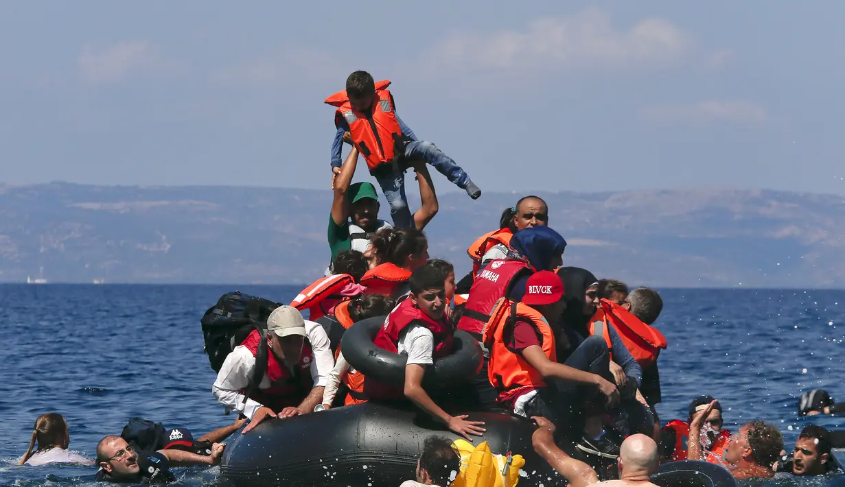 Seorang pengungsi mengangkat anaknya saat perahu mereka kempes di Pulau Lesbos, Yunani (13/9/2015). Menurut Organisasi Internasional untuk Migrasi (IMO) diperkirakan 309.000 orang telah tiba melalui laut di Yunani (REUTERS / Alkis Konstantinidis)