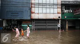 Warga melintasi genangan banjir di Jalan Gunung Sahari, Jakarta, Kamis (21/4/2016). Hujan yang mengguyur Jakarta sejak tadi malam membuat beberapa ruas jalan Jakarta tergenang banjir. (Liputan6.com/Faizal Fanani)