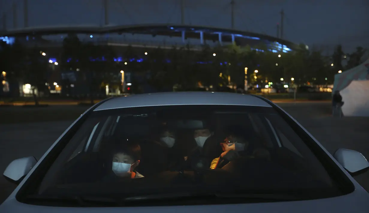 Anggota keluarga di dalam mobil menonton sirkus drive-in dari tempat parkir di Seoul, Korea Selatan, Jumat (25/9/2020). Acara ini digelar untuk memberikan hiburan bagi orang-orang selama wabah virus corona. (AP Photo/Ahn Young-joon)